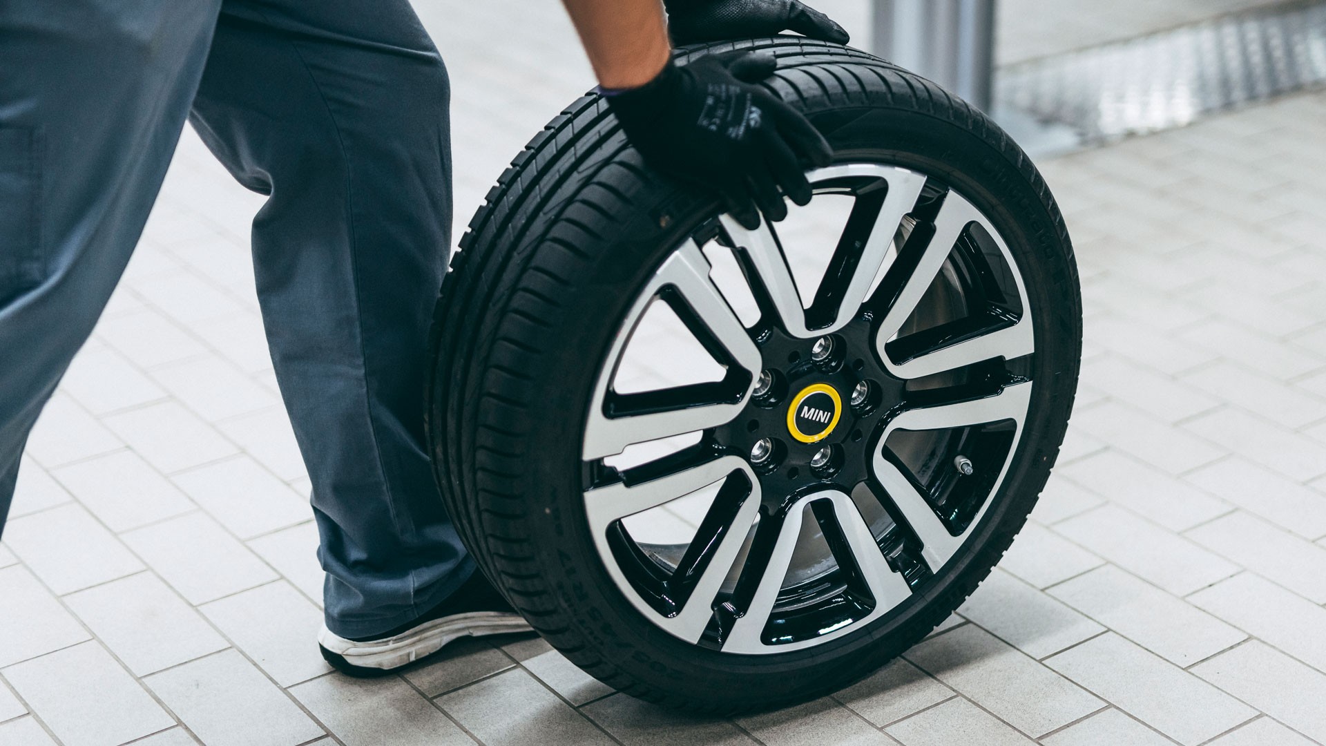 Zamestnanec servisného strediska MINI vymieňajúci koleso.